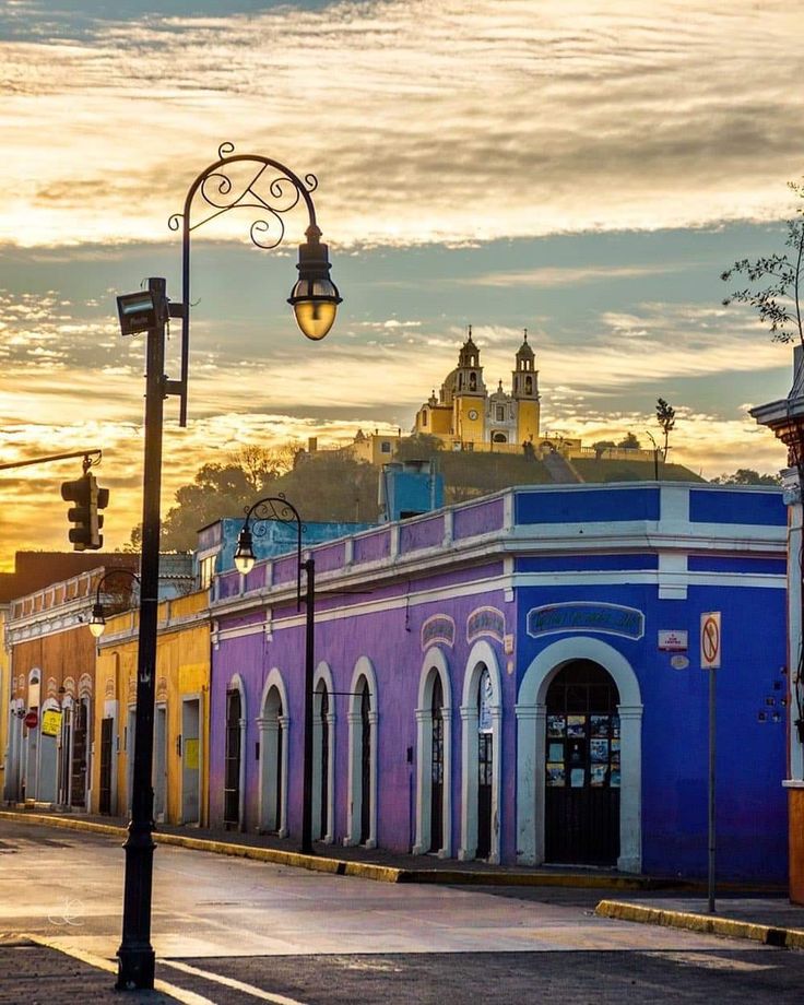 an empty street with colorful buildings in the background and a lamp post on the corner