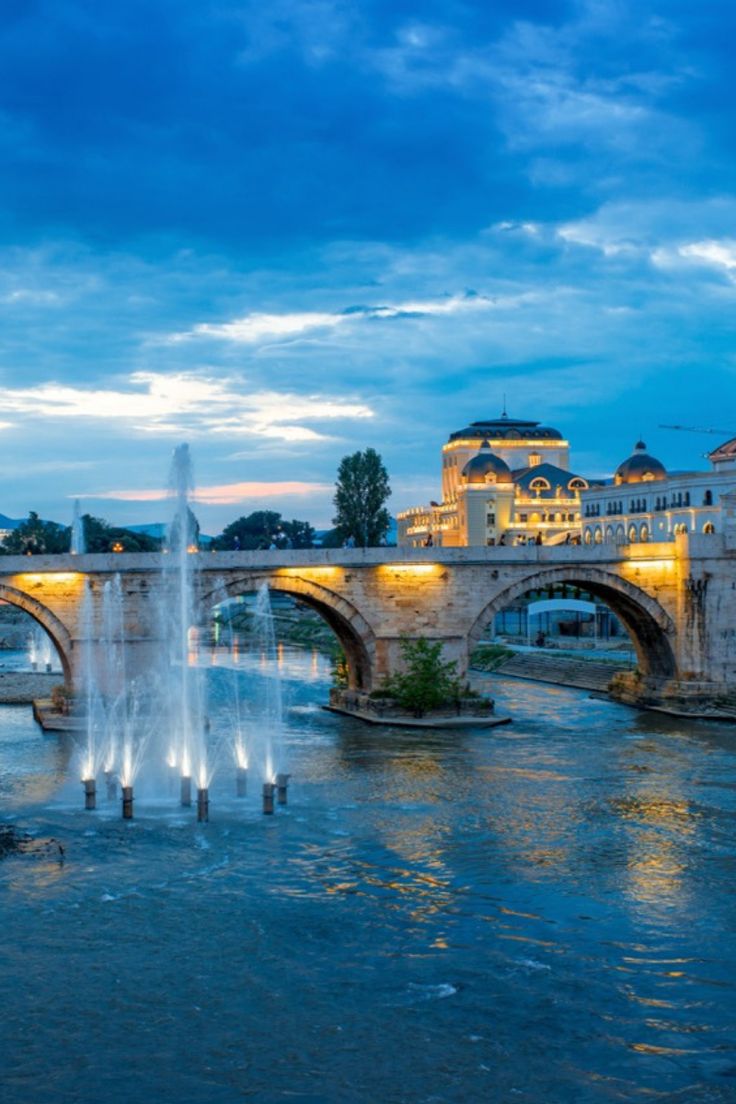 a bridge over a river with a fountain in front of it