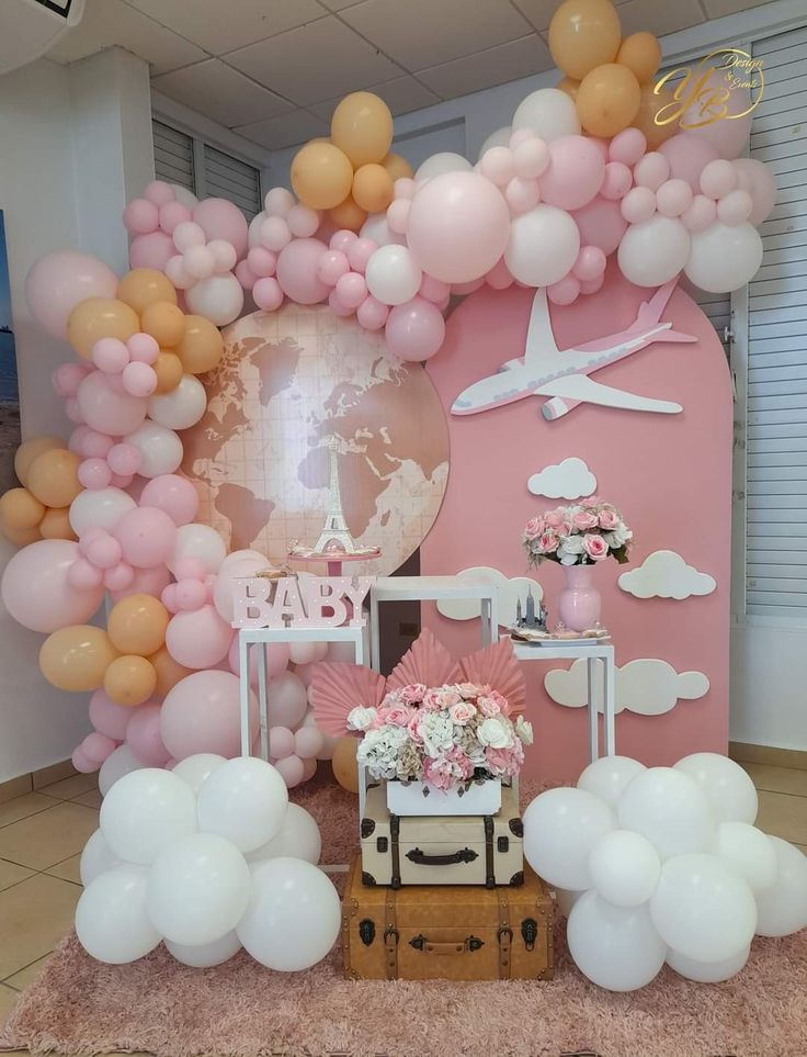 a pink and gold baby shower party with balloons, flowers, and decorations on the wall