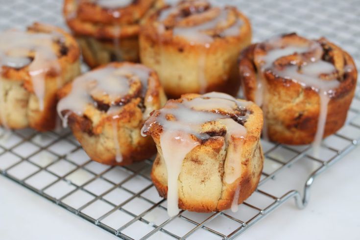 several cinnamon rolls on a cooling rack with icing drizzled over them