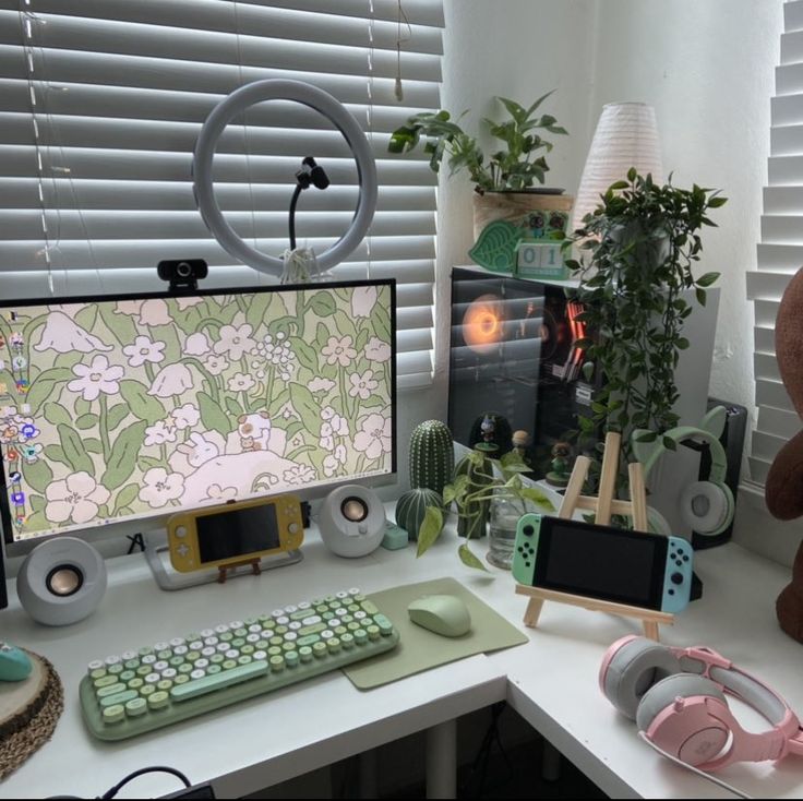 a desk with a computer monitor, keyboard and headphones on it next to a teddy bear