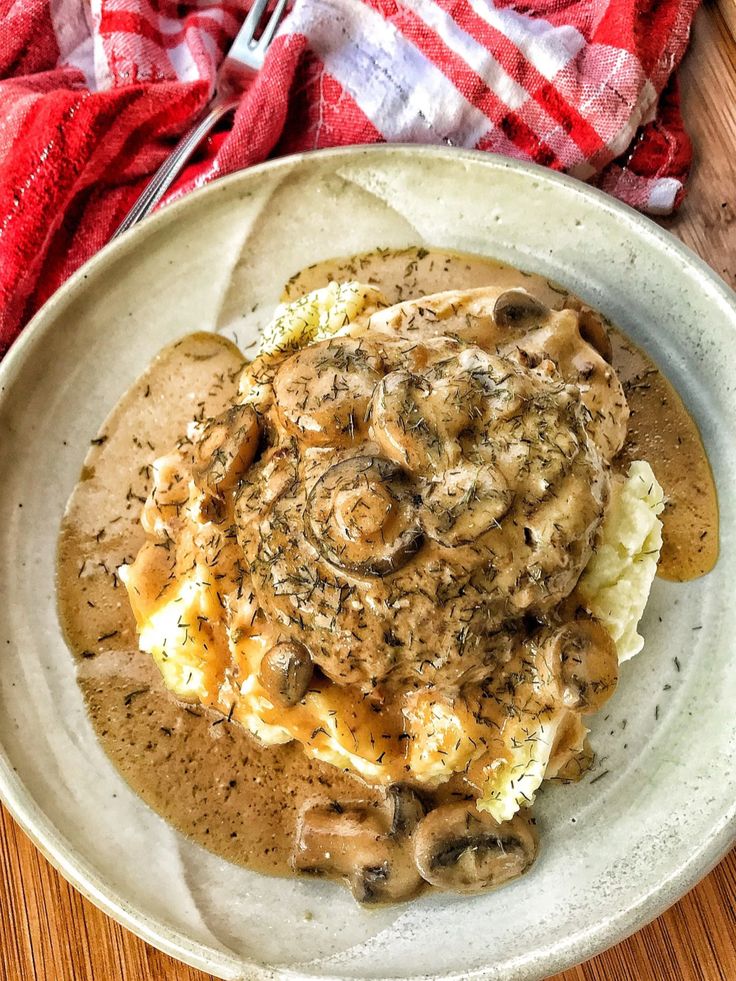 a white plate topped with mashed potatoes covered in mushroom gravy and sauce