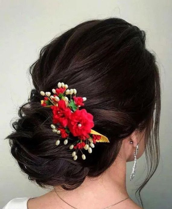 a woman wearing a red flower hair comb