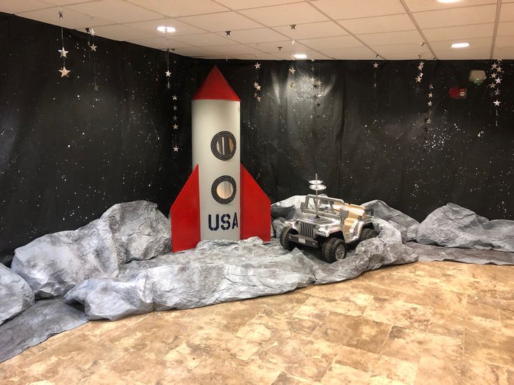 a space shuttle on display in a room with black walls and stars hanging from the ceiling