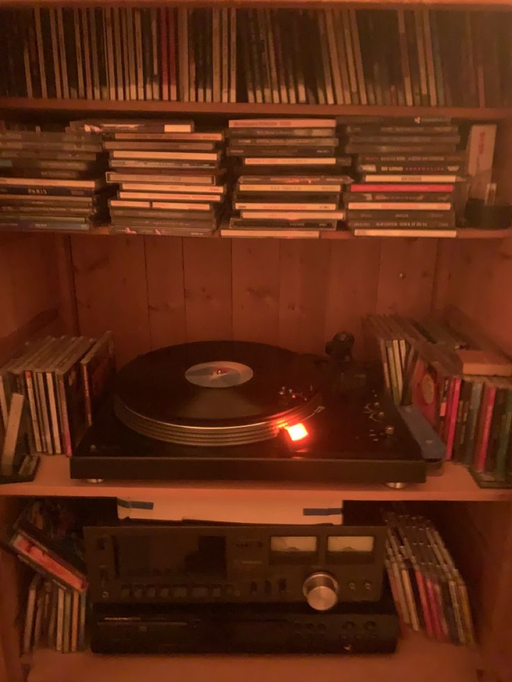 a record player is sitting on top of a shelf full of cd's and cds