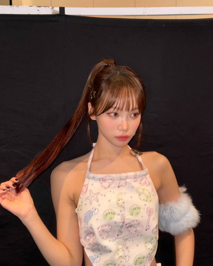 a woman with long hair standing in front of a black backdrop