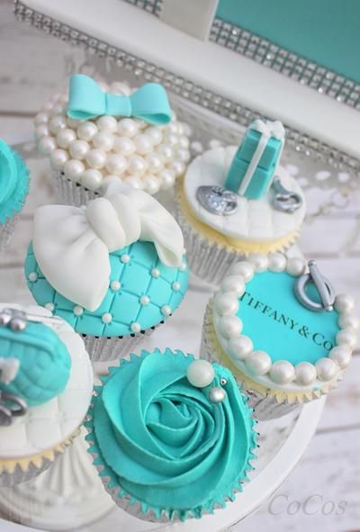 cupcakes decorated with blue and white frosting are on a cake platter