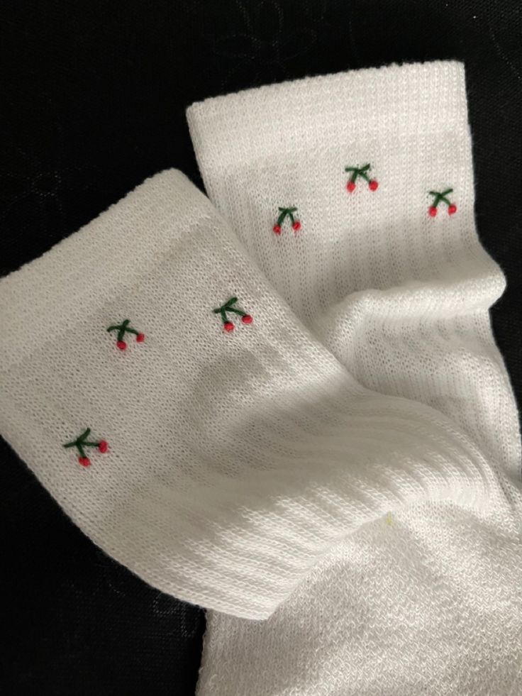 two white knitted napkins with cherries on them sitting next to each other