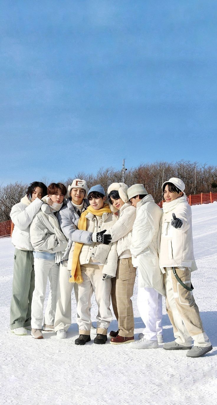 a group of young people standing next to each other on top of snow covered ground