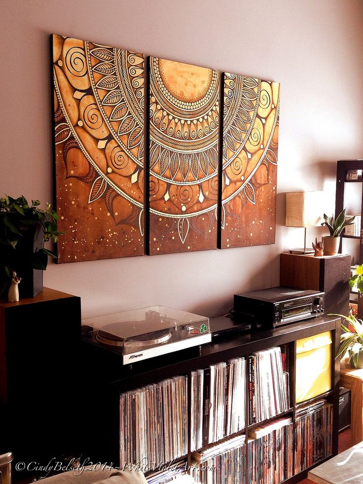 three paintings are hanging on the wall above a record player