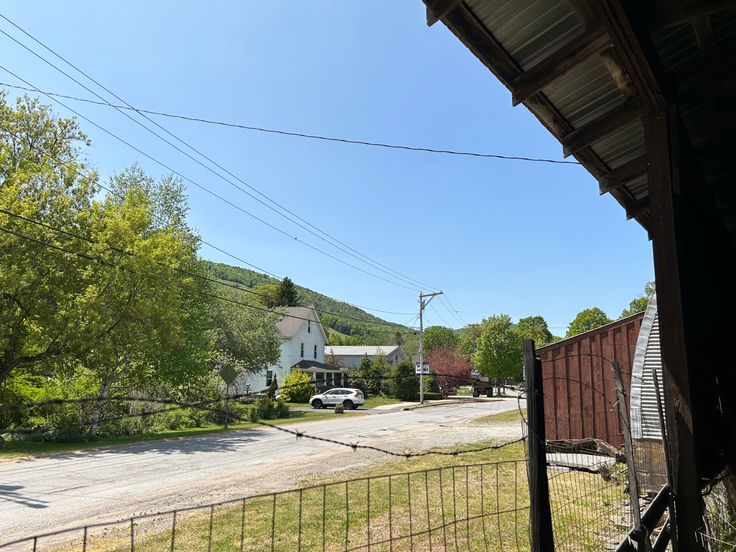 an empty street with cars parked on the side of it and houses in the background