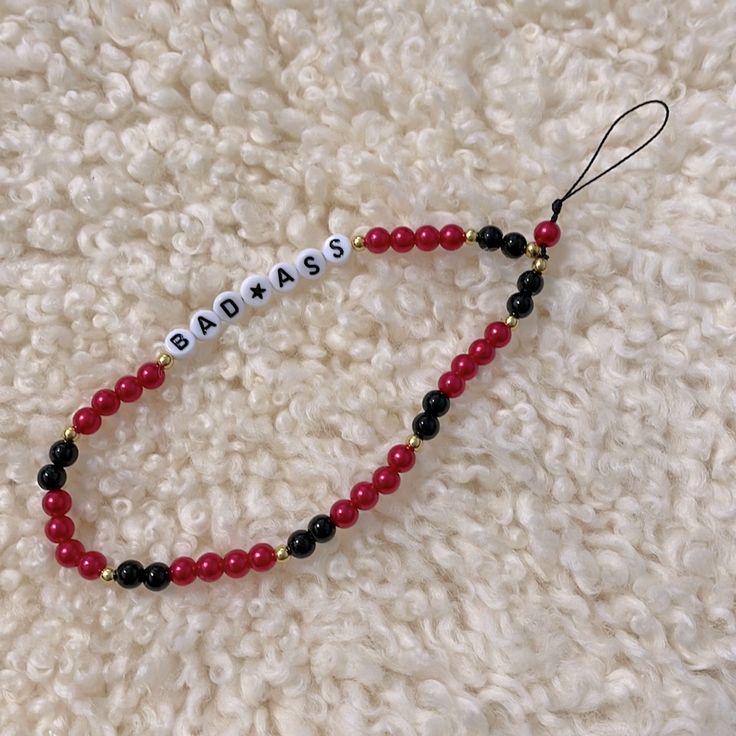 a red beaded necklace with black beads and the word asasa written on it