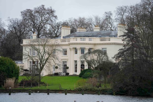 a large white house sitting on top of a lush green field next to a lake