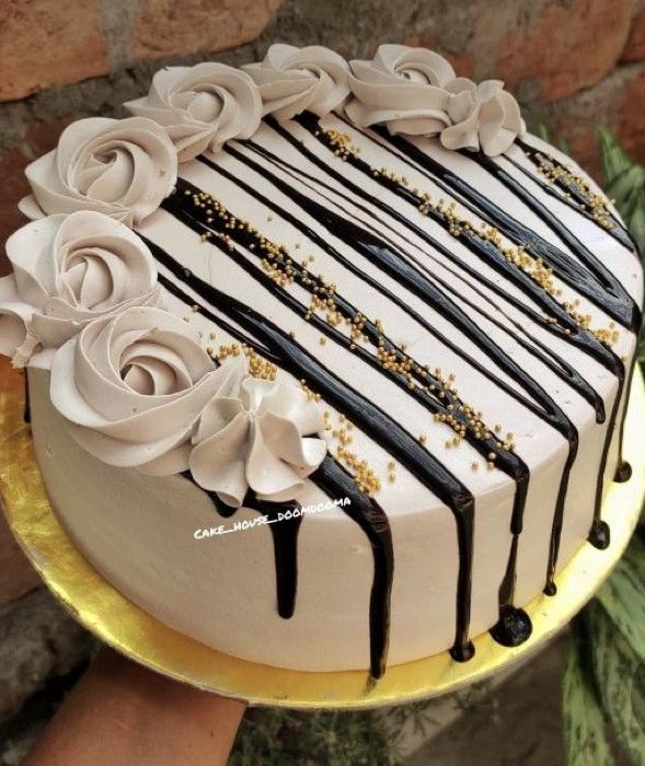 a cake with white and black icing on it sitting on a gold platter