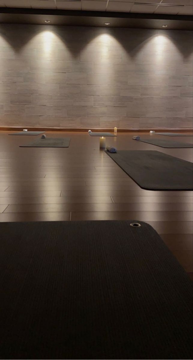 an empty room with yoga mats on the floor and lights in the wall behind it