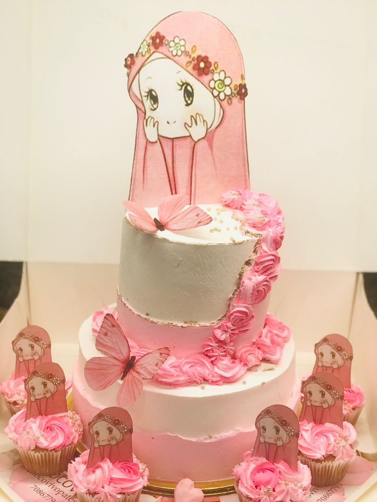 there is a cake with pink frosting and decorations on the bottom tier, along with cupcakes