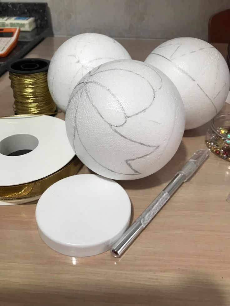 some white balls sitting on top of a table next to spools of thread