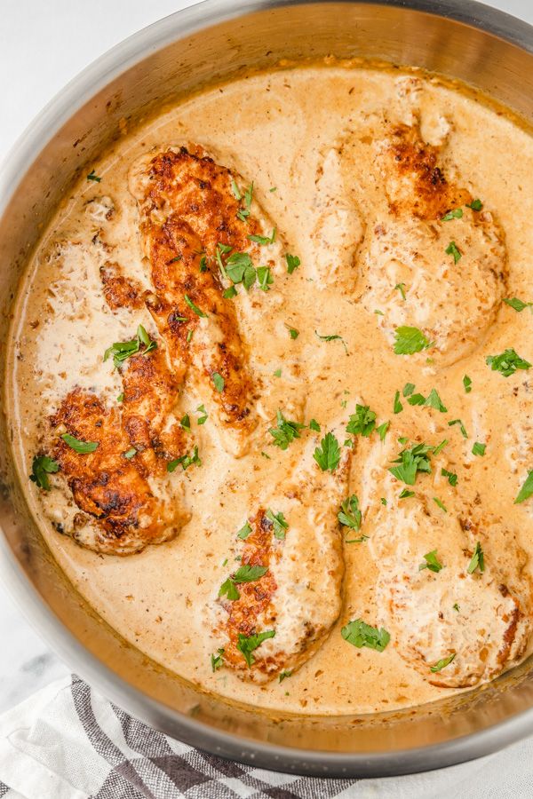 a pan filled with meat covered in gravy and garnished with parsley