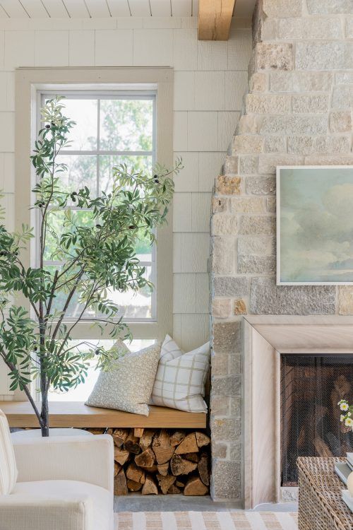 a living room filled with furniture and a fire place next to a tree in front of a window