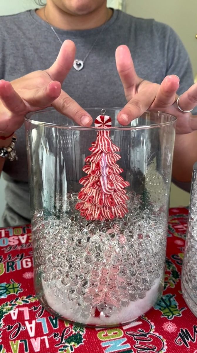 a man is making a christmas tree out of candy canes in a glass cup