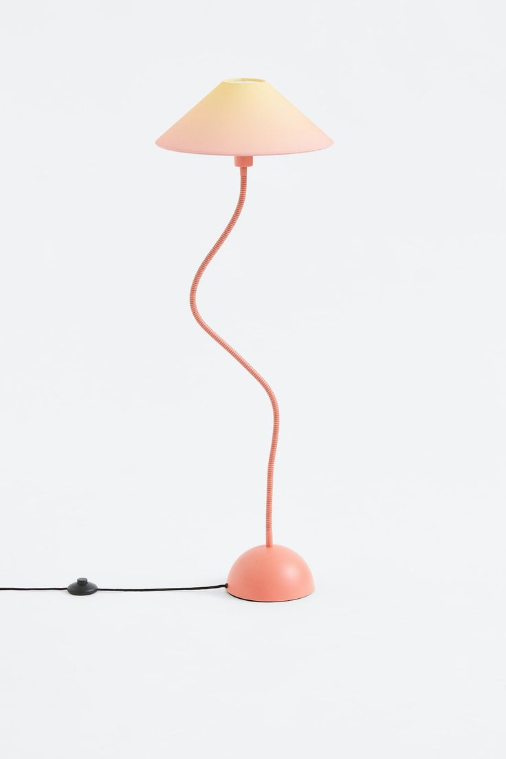 a pink lamp on a white surface with a cord running through it and a light bulb plugged in