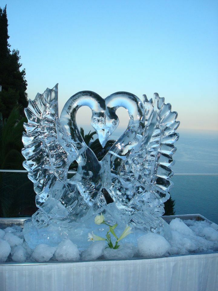 an ice sculpture in the shape of two hearts on top of a table with water and snow around it