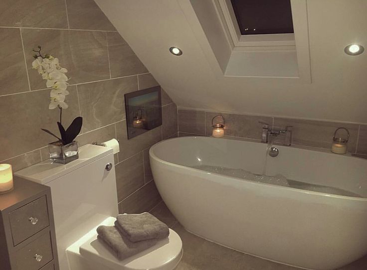 a white bath tub sitting under a window next to a toilet