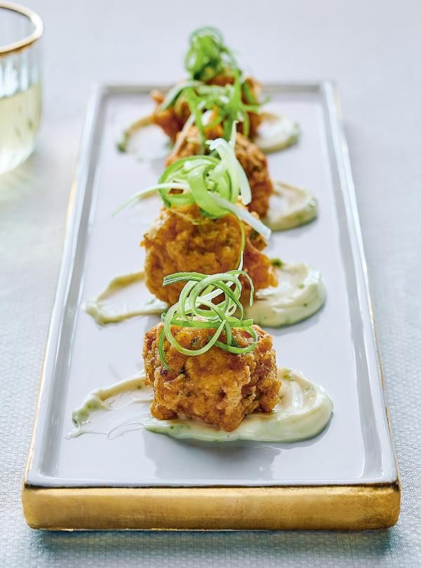 several appetizers are arranged on a long white plate with green garnishes