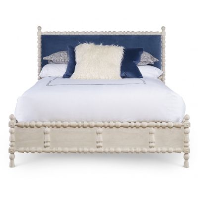 a white bed with blue and white pillows on it's headboard is shown