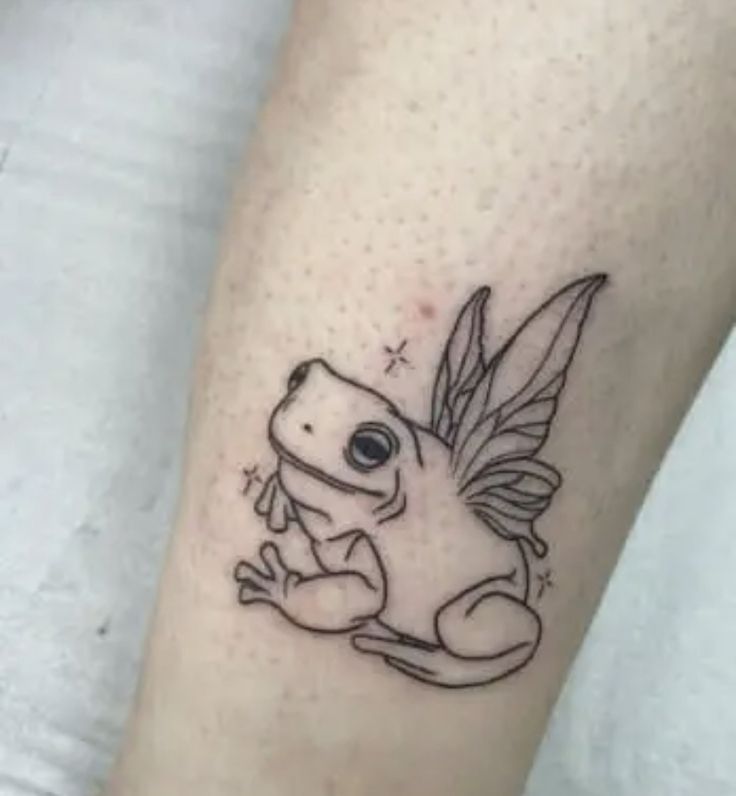 a tattoo on the leg of a person with a small frog sitting on top of it