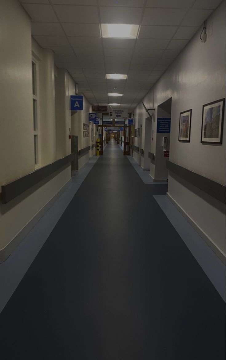 an empty hospital hallway with pictures on the walls