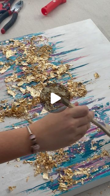 a person is painting with gold leafy paint