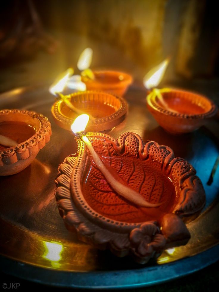 candles are lit on a metal tray in the middle of a circle with an intricate design