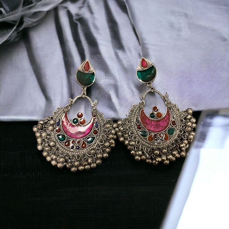 The Pink Gul Chandbali Earrings features intricate flower and peacock design on Oxidized Silver with multicolor crystals. The addition of ghungroos completes the look of this chandbali. Specifications Materials used: Oxidized Silver, Meenakari, Ghungroos At Romikas, we pride ourselves on the craftsmanship and high quality of our jewelry, designed to enhance your natural beauty. Please contact us with any questions. Multicolor Chandbali Earrings With Intricate Design, Multicolor Intricate Earrings For Navratri, Multicolor Chandbali Earrings With Peacock Design, Multicolor Peacock Chandbali Earrings, Multicolor Peacock Design Chandbali Earrings, Multicolor Peacock Design Earrings For Festivals, Ornate Meenakari Chandbalis For Festivals, Bollywood Style Multicolor Chandbalis With Intricate Design, Ornate Chandbali Danglers For Festivals