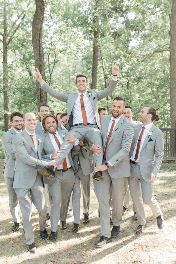 a group of men in suits and ties are posing for a photo with one man on his shoulders