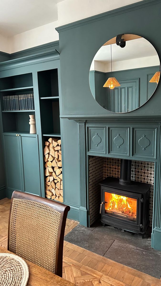 a living room with a fire place next to a mirror on the wall and a chair in front of it