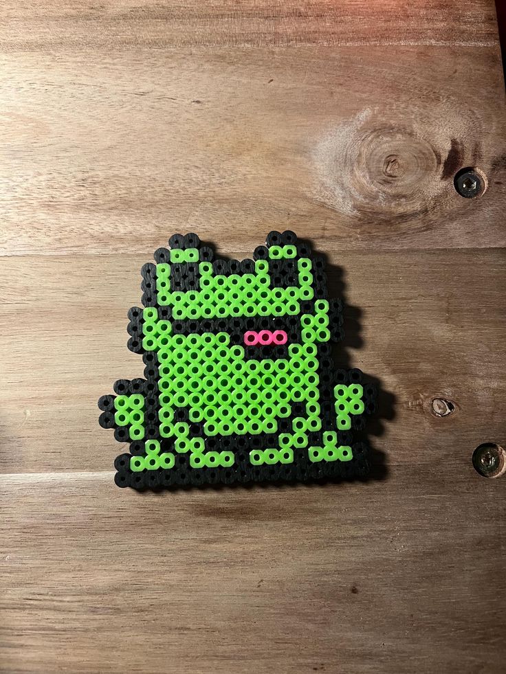 a piece of green bead art sitting on top of a wooden table