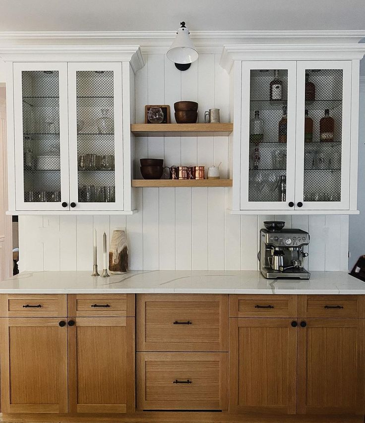 a kitchen with wooden cabinets and white counter tops, along with glass front cupboards