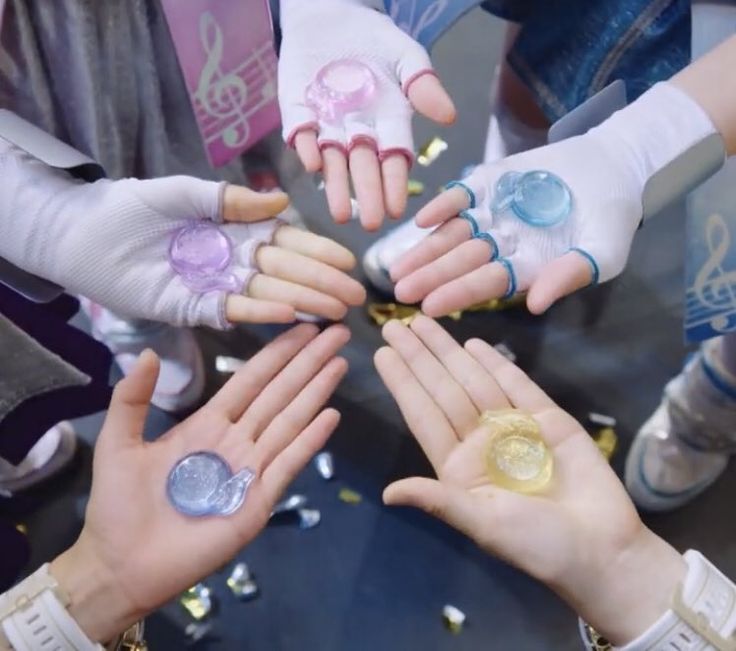 many people are holding their hands together in a circle with confetti on them