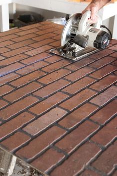 a person using a power tool on a brick floor