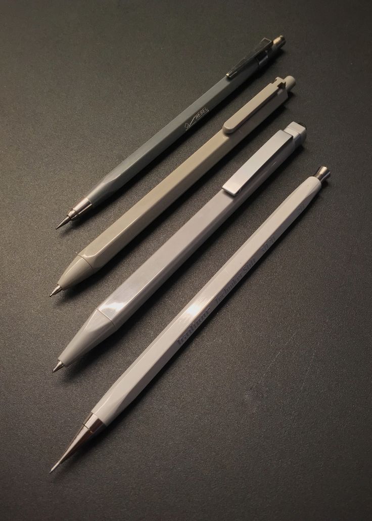 three different pens are lined up next to each other on a black surface with one pen in the middle