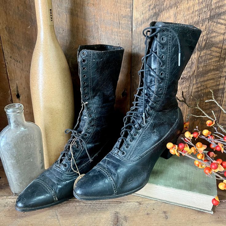 a pair of black boots sitting on top of a wooden floor next to a bottle