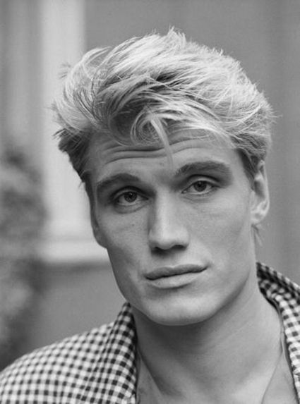 a black and white photo of a man with blonde hair wearing a checkered shirt