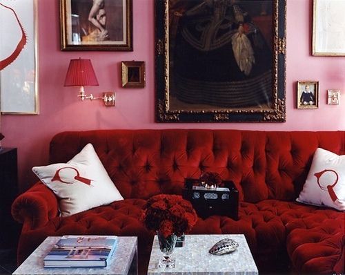 a living room with red couches and pictures on the wall