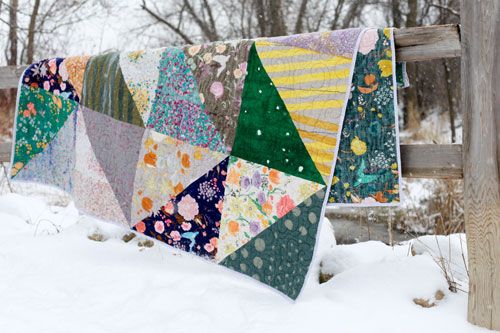 a quilt hanging from a wooden fence in the snow