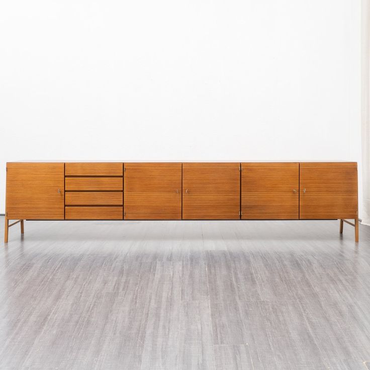 a wooden cabinet sitting on top of a hard wood floor next to a white wall