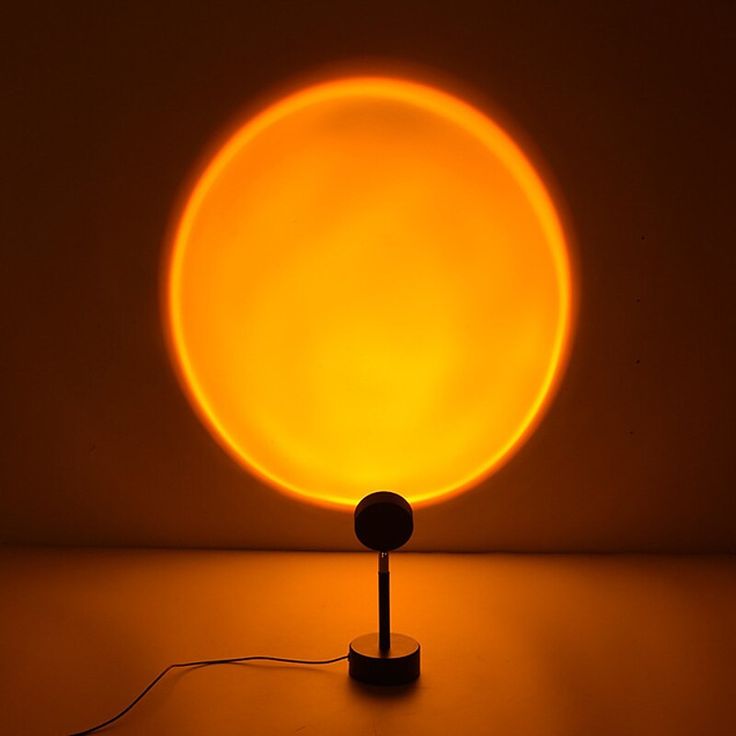 a yellow light is shining on the floor in front of a black background with a round object