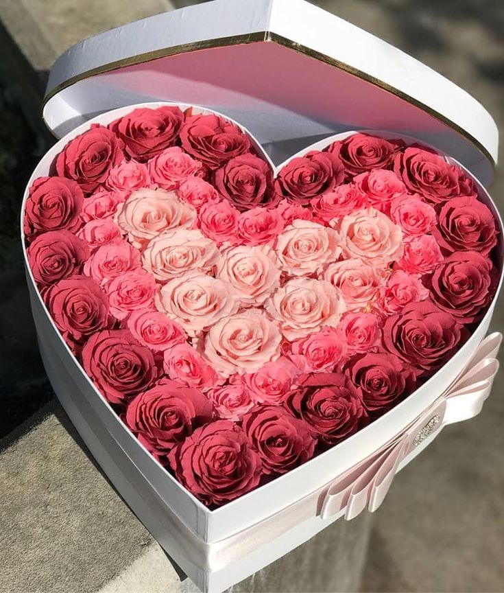 a heart shaped box filled with pink roses