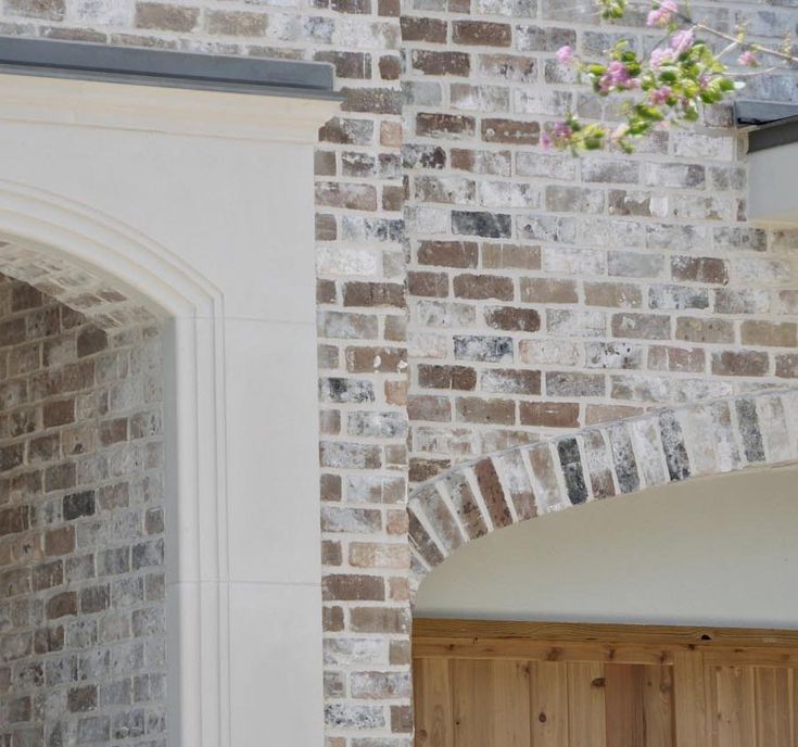 an open door in front of a brick wall with flowers hanging from the top and bottom