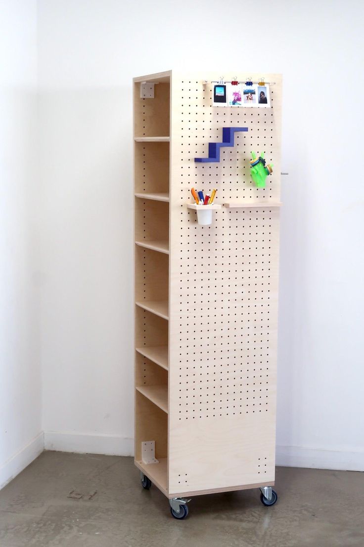 a wooden shelf with pegboard on it in the corner next to a white wall